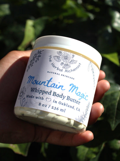 A jar of mountain magic whipped body butter, scented with a blend of eucalyptus, lavender, bergamot, and patchouli. The fragrance is fresh, earthy, and bright, with subtle cool notes reminiscent of a refreshing mountain breeze.